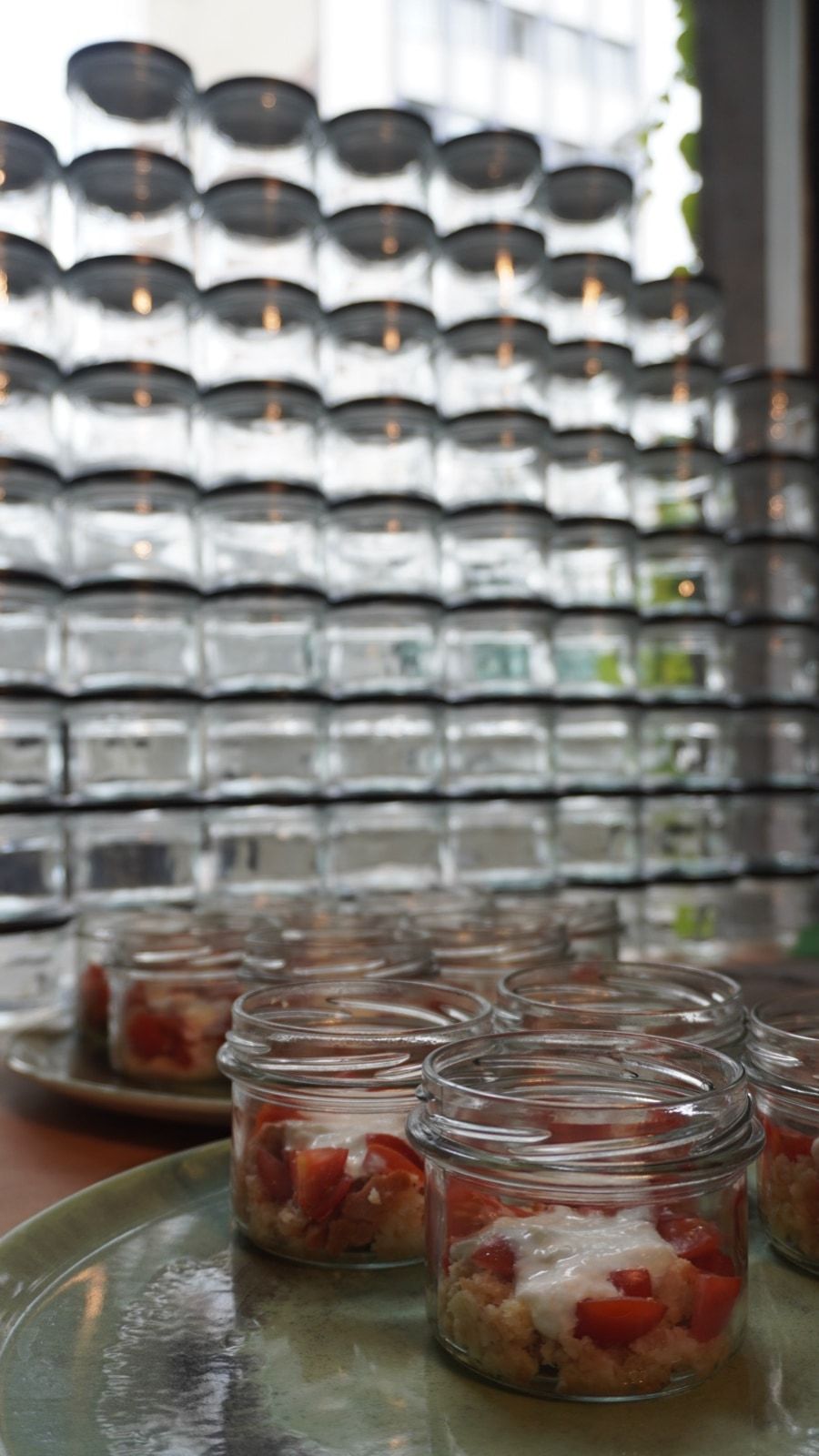Erdbeer-Tiramisù im Glas vor gestapelten Einmachgläsern